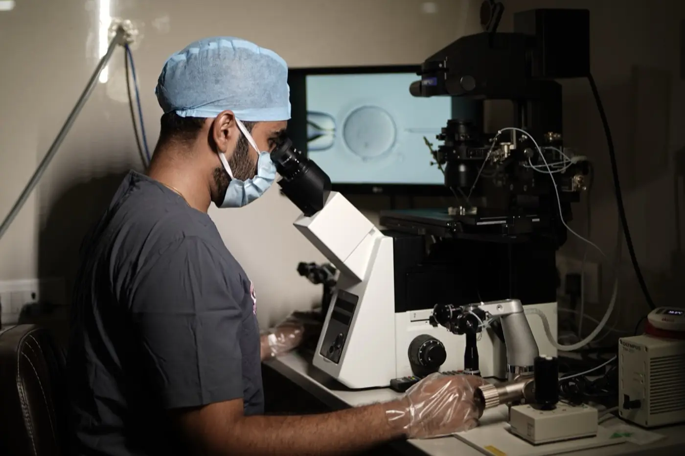 Aayush Agarwal, Ph.D., at the inverted microscope with a live embryo view on screen in the Aansh IVF embryology lab